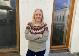 En kvinne i strikket genser foran en vegg